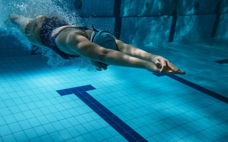 Frau taucht nach Startsprung ins Wasser ein