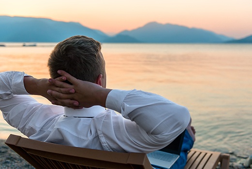 Mann liegt auf einer Liege am See und entspannt