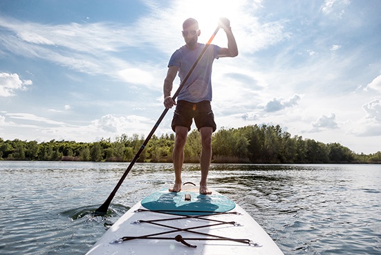Mann beim Stand up Paddling im See