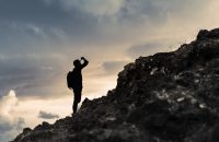 Man getting ready to climb up mountain looking up at the challen