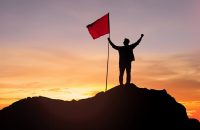 silhouette of businessman with flag on top mountain sky and sun light background business success